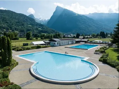 a large swimming pool with mountains in the background at Mobil home 4 personnes au pied du Grand Massif à Samoëns in Samoëns