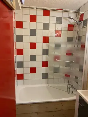 a bath tub in a bathroom with red and white tiles at Studio Samoens 1600 pied des pistes in Samoëns