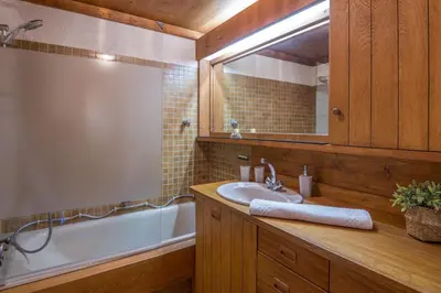 a bathroom with a sink and a tub and a mirror at Appartement Pruniers - Welkeys in Megève