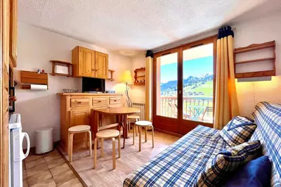 a living room with a couch and a kitchen with a table at Bright apartment with Mont Blanc view in Combloux