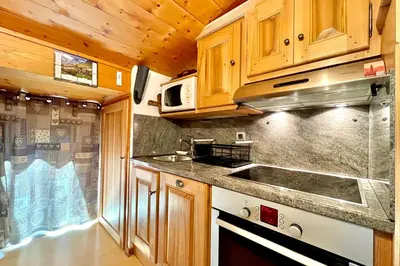 a kitchen with wooden cabinets and a sink at Le Grenier du Feug in Combloux