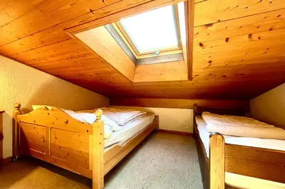 a bedroom with two beds in a wooden attic at Le Grenier du Feug in Combloux