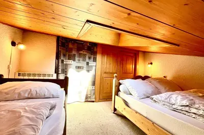 two beds in a room with wooden walls at Le Grenier du Feug in Combloux