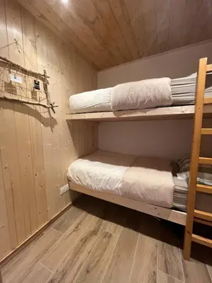 a room with two bunk beds and a wooden floor at Appartement au centre des Carroz in Arâches-la-Frasse