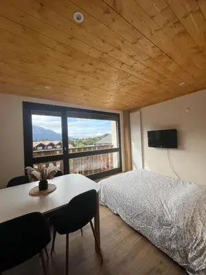 a bedroom with a bed and a table and a large window at Appartement au centre des Carroz in Arâches-la-Frasse
