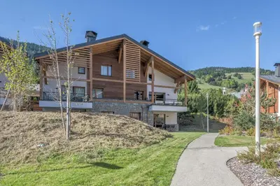 a house on top of a hill with a driveway at Appartement Havre des Alpes - Welkeys in Megève