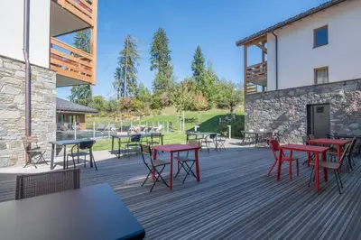 a deck with tables and chairs and a building at Appartement Havre des Alpes - Welkeys in Megève