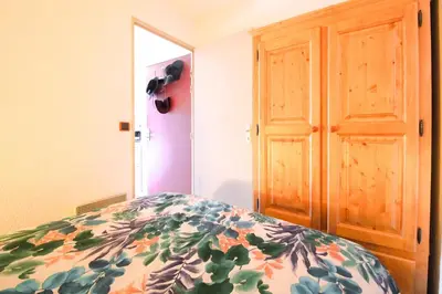 a bedroom with a bed and a wooden door at Studio cabine lumineux et calme, au centre de Flaine Foret in Flaine