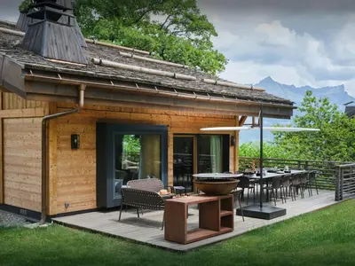 a house with a deck with a grill and a table at Chalet RevAlp - OVO Network in Combloux