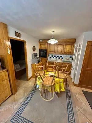 a kitchen with wooden cabinets and a table and chairs at gîte 6 pers RC domaine skiable Grand Massif les Carroz Flaine Morillon Samoens in Les Carroz d'Araches