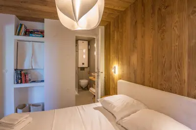 a bedroom with a white bed and a chandelier at Appartement Rosset - Welkeys in Megève