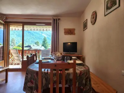 a dining room with a table and a television and a window at T3 calme à Samoëns, proche centre, WIFI, parking privé - FR-1-629-150 in Samoëns