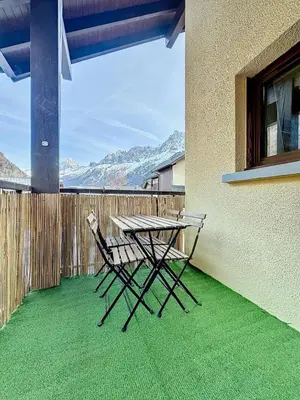 a picnic table and chair on a balcony with mountains at Modern 2BR Apt with Mountain Views & Private Parking in Les Houches