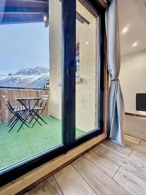 a room with a large window with a table and a balcony at Modern 2BR Apt with Mountain Views & Private Parking in Les Houches