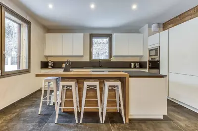 a kitchen with white cabinets and bar stools at Luxurious Chalet Verney - 8 people in Chamonix-Mont-Blanc