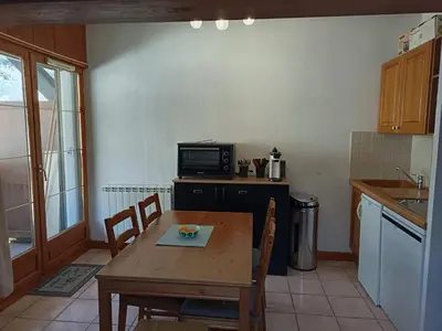 a kitchen with a wooden table and a table and a microwave at Les Contamines Montjoie in Le Cugnon