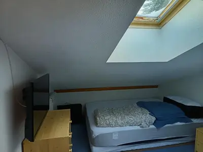a small bedroom with a bed and a skylight at Les Contamines Montjoie in Le Cugnon