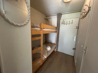 a small room with bunk beds in a room with a door at Petit appartement cosy in Les Contamines-Montjoie