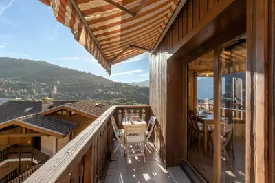 a balcony of a wooden house with a table and chairs at Le Mont Joux - Vue montagne in Saint-Gervais-les-Bains