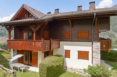 a large wooden house with a balcony and a table at Tete Rousse - Ski aux pieds - Piscine - Terrace in Les Houches