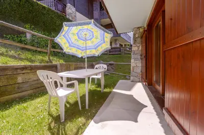a table with two chairs and an umbrella on a yard at Tete Rousse - Ski aux pieds - Piscine - Terrace in Les Houches