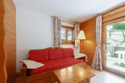 a red couch in a room with a window at Tete Rousse - Ski aux pieds - Piscine - Terrace in Les Houches