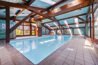 a large indoor swimming pool with wooden ceilings at Tete Rousse - Ski aux pieds - Piscine - Terrace in Les Houches