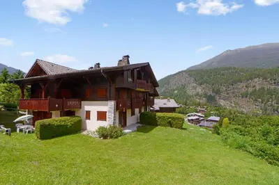 a house on top of a grassy hill at Tete Rousse - Ski aux pieds - Piscine - Terrace in Les Houches