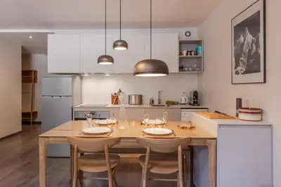 a kitchen with a wooden table and chairs in a kitchen at Appt Cosy - Vue Mont-Blanc en hyper centre in Chamonix-Mont-Blanc