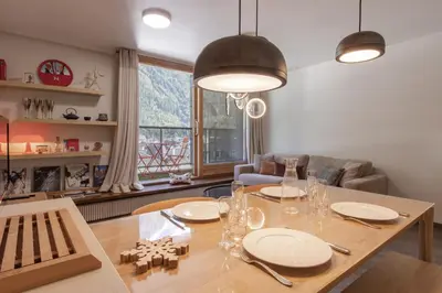 a dining room with a table with plates and glasses at Appt Cosy - Vue Mont-Blanc en hyper centre in Chamonix-Mont-Blanc