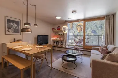a living room with a table and a couch at Appt Cosy - Vue Mont-Blanc en hyper centre in Chamonix-Mont-Blanc