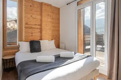 a bedroom with a large bed with a large window at Au coin du feu - Terrasse - Vue Mont Blanc in Saint-Gervais-les-Bains