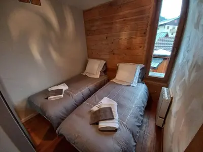 two twin beds in a small room with a window at Au coin du feu - Terrasse - Vue Mont Blanc in Saint-Gervais-les-Bains