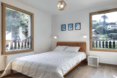 a bedroom with a bed and two large windows at Mountain Lodge 204 - 90m2 - à côté du télésiège in Saint-Gervais-les-Bains