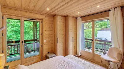 a room with a bed and a balcony with windows at 1 Gentil Homme in Megève