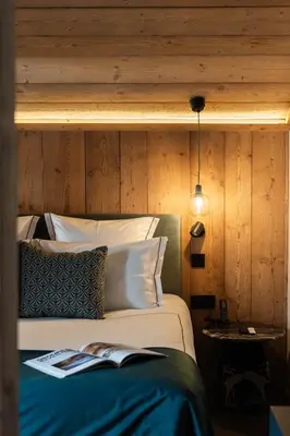 a bedroom with a bed with a wooden wall at Chalet L'Écrin de Megève in Megève