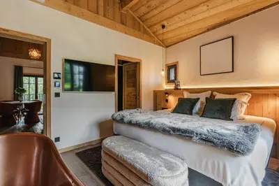a bedroom with a large bed and a chair at Chalet L'Écrin de Megève in Megève