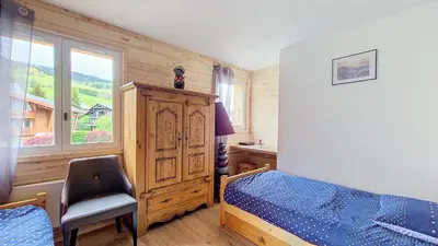 a bedroom with a bed and a chair and a window at 1 Clos des Mourets C2 in Megève