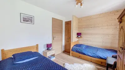a bedroom with two beds and a wooden wall at 1 Clos des Mourets C2 in Megève