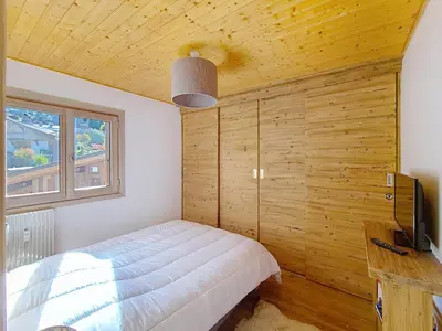 a bedroom with a bed with a wooden wall at 1 Chalet de Rochebrune B in Megève
