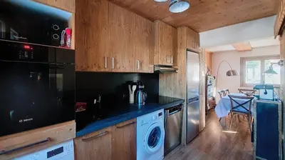 a kitchen with wooden cabinets and a washer and dryer at 1 Chalet de Rochebrune B in Megève