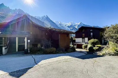 a balcony with a table and chairs with mountains in the background at Stay in the heart of Chamonix-Mont-Blanc in Chamonix-Mont-Blanc