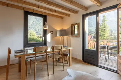 a dining room with a table and chairs and windows at Le Refuge des Pecles, chalet avec vue Mont-Blanc in Chamonix-Mont-Blanc