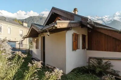 a small white house with mountains in the background at Le Refuge des Pecles, chalet avec vue Mont-Blanc in Chamonix-Mont-Blanc