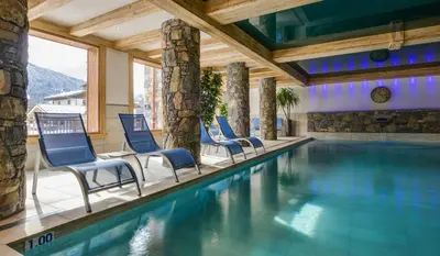 a pool in a hotel with chairs and a swimming pool at CGH Résidence Boutique Les Chalets De Laÿssia in Samoëns
