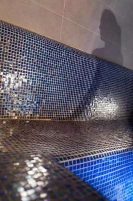 a shadow of a person sitting on a blue tiled tub at CGH Résidence Boutique Les Chalets De Laÿssia in Samoëns