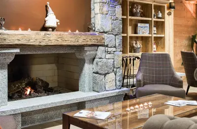 a fireplace in a living room with chairs and a table at CGH Résidence Boutique Les Chalets De Laÿssia in Samoëns