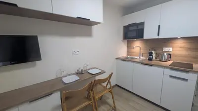 a kitchen with white cabinets and a table and chairs at Studio La Vallée Blanche in Sallanches