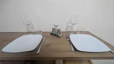 a wooden table with two white plates and wine glasses at Studio La Vallée Blanche in Sallanches
