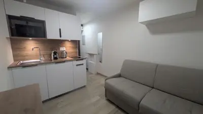 a living room with a couch and a kitchen at Studio La Vallée Blanche in Sallanches